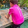 activity, back_view, black_shorts, boy, casual_clothing, child, curious, daylight, exploration, grass, greenery, nature, outdoor, pink_shirt, pond, shoes, summer, under_armour, wooden_plank, young