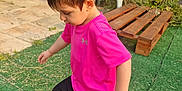 Ewenn a rejoint le concours — aidez-le/la à gagner de superbes lots ! black_shorts, boy, bracelet, casual_clothing, child, curious, daylight, footwear, garden, grass, greenery, nature, outdoor, pink_shirt, plants, plastic_chair, playing, side_view, stone_wall, young