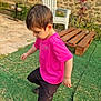 black_shorts, boy, bracelet, casual_clothing, child, curious, daylight, footwear, garden, grass, greenery, nature, outdoor, pink_shirt, plants, plastic_chair, playing, side_view, stone_wall, young