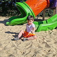 Ewenn a rejoint le concours — aidez-le/la à gagner de superbes lots ! casual_clothing, child, daylight, footwear, fun, greenery, kid, nature, orange_shorts, outdoor, park, playground, playing, recreation, sand, slide, summer, sunlight, trees, white_tshirt