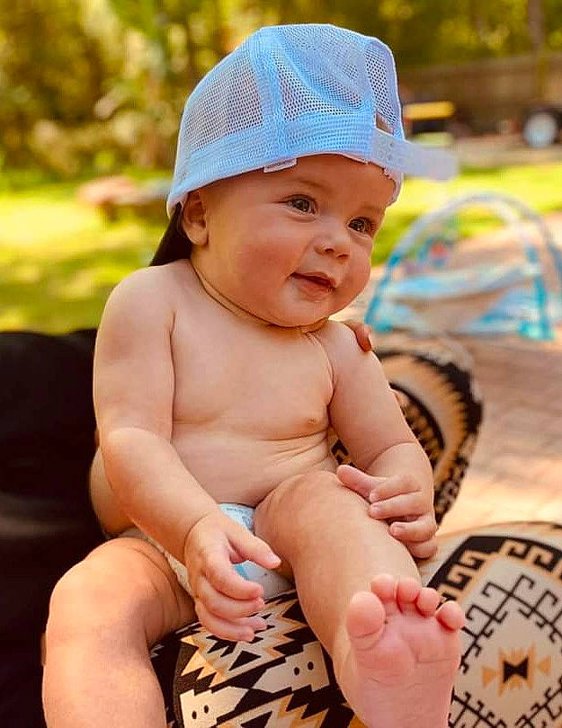 Cannon is registered to the contest to win money with this photo: arm, baby, baby_toddler_clothing, cap, child, face, finger, fun, grass, hand, happy, hat, headwear, human_leg, leg, leisure, person, product, skin, thigh