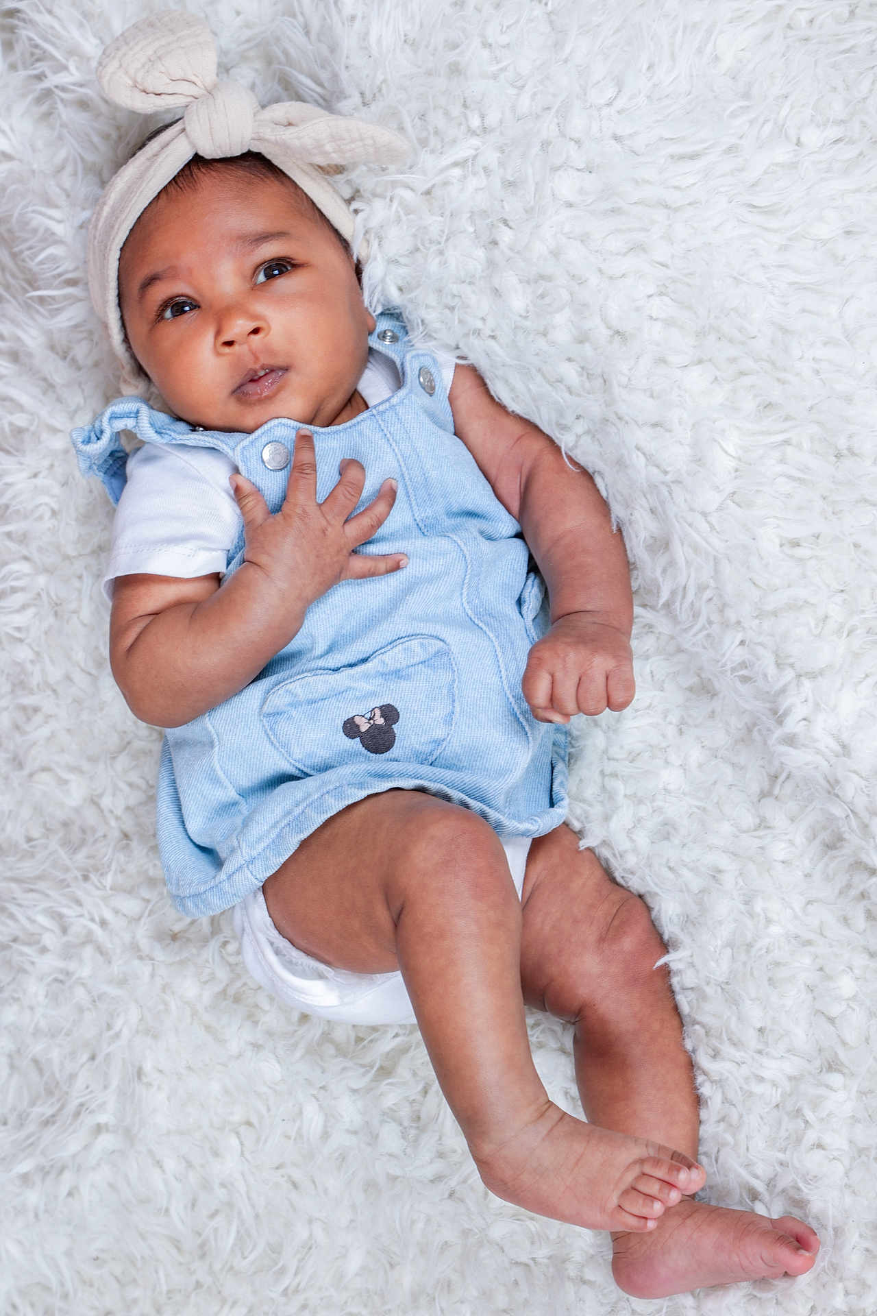 Layana participe au concours pour gagner de l'argent avec cette photo : baby, blanket, blue_dress, bow, child, clothing, cute, expression, fluffy, foot, hand, headband, indoor, infant, legs, lying_down, minnie_mouse, portrait, skin, white
