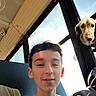 boy, casual, clothing, digital_overlay, dog, face, guide_dog_emoji, hair, indoors, light, portrait, seat, selfie, shadow, skin, smile, sunlight, vehicle_interior, window, young_person