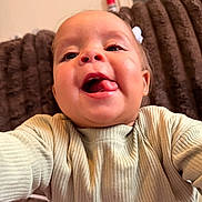 Xiomora is registered to the contest to win money with this photo: toddler, child, face, tongue, sweater, ribbed_clothing, smile, happy, indoors, plush_background, person, cute, playful, portrait, baby, earrings, long_eyelashes, furniture, fire_extinguisher, selfie