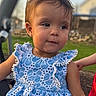toddler, child, blue_dress, outdoor, grass, curious_expression, phone_screenshot, app_icons, status_bar, person, young_child, portrait, summer, casual, daylight, cute, small_child, face, standing, natural_light