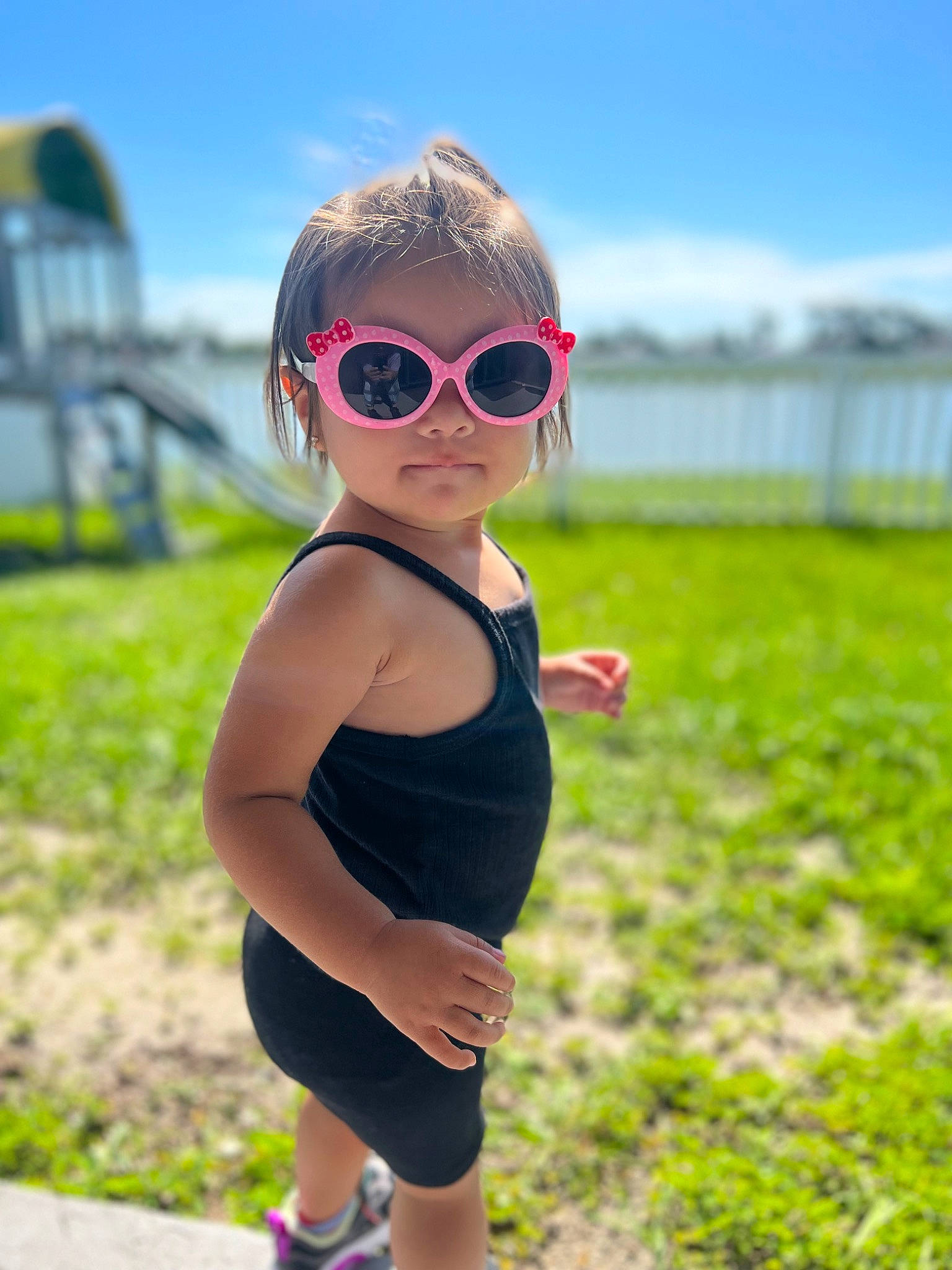Alaia is registered to the contest to win money with this photo: cool, eyewear, glasses, goggles, grass, hairstyle, hand, happy, head, human_body, leisure, people_in_nature, person, plant, sky, sleeve, sportswear, sunglasses, toddler, vision_care