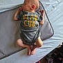 newborn, baby, sleeping, onesie, pacifier, bed, tissue_box, feet, hands, clothing, infant, cute, resting, indoor, soft, grey, yellow_text, crib_mat, peaceful, child