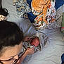 Elliot is registered to the contest to win money with this photo: newborn, baby, woman, glasses, bed, blanket, towel, elephant, cozy, pillow, indoor, person, child, sleeping, wrapped, soft, colorful, patterned, comfort, caring