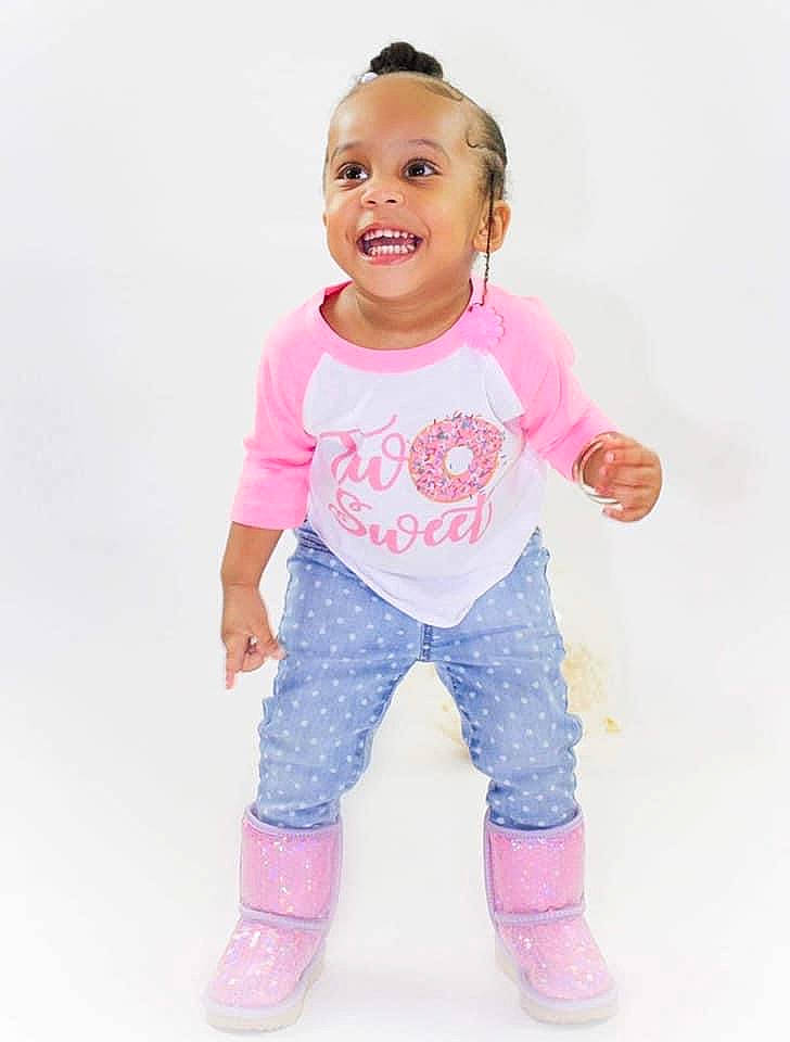 Damya is registered to the contest to win money with this photo: arm, baby_toddler_clothing, cheek, child, denim, face, gesture, hair, happy, head, human_body, joy, magenta, peach, person, pink, sleeve, smile, sock, t_shirt