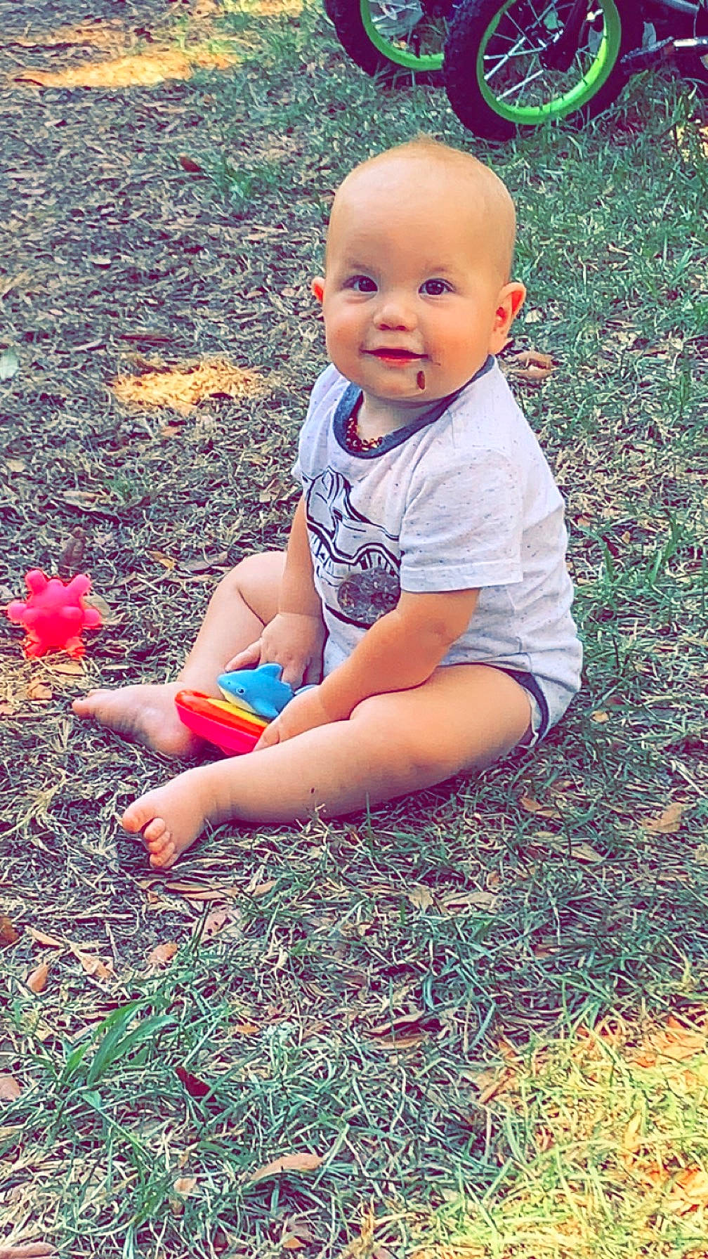 Nolan joined the competition — help win amazing prizes! baby, clothing, face, grass, head, machine, nature, outdoors, park, person, photography, plant, portrait, shorts, sitting, soil, summer, t_shirt, wheel, yard