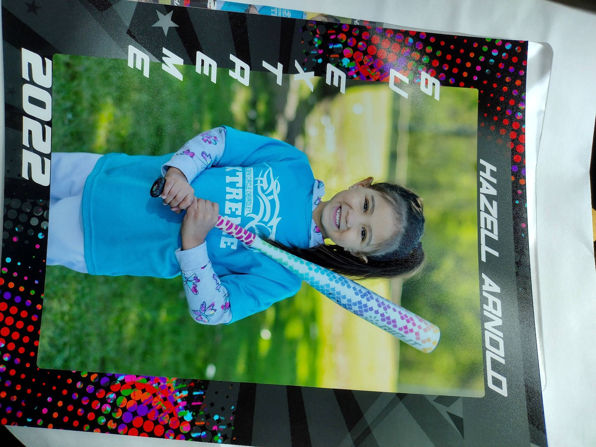 Hazell is registered to the contest to win money with this photo: advertising, art, banner, child, display_device, entertainment, event, font, fun, grass, happy, joy, leisure, pattern, person, public_event, rectangle, smile, stage_equipment, t_shirt