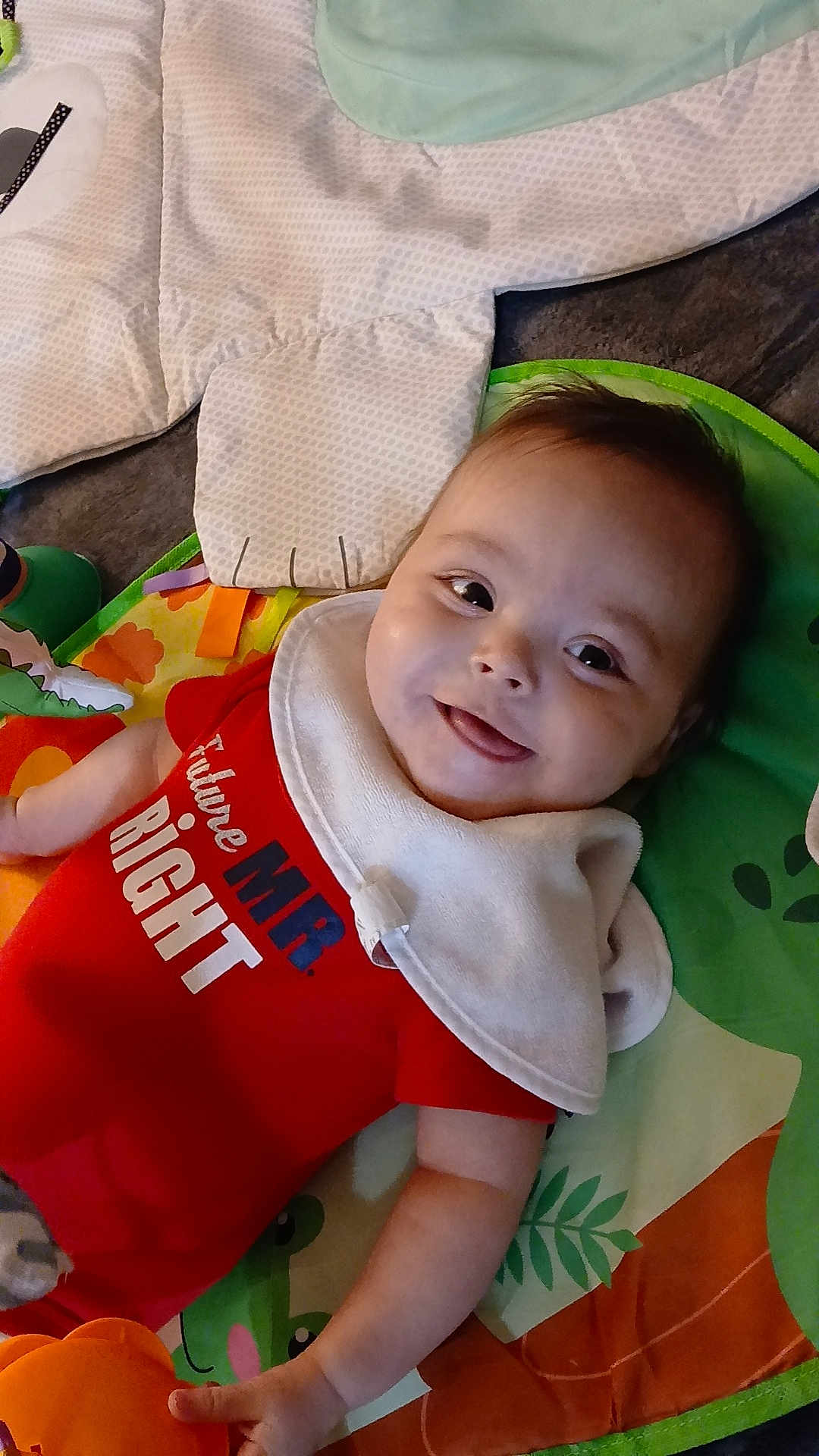 Onyx joined the competition — help win amazing prizes! baby, child, smiling, onesie, bib, play_mat, toy, infant, lying_down, happy, cute, face, skin, arm, hand, clothing, indoor, colorful, soft_toy, blanket