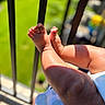 baby, legs, feet, infant, skin, sunlight, shadow, outdoor, railing, blurred_background, child, closeup, toddler, summer, warm, playful, small, human_limb, baby_clothing, soft
