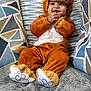 baby, child, lion_costume, orange, plush, couch, pillow, pattern, happy, smiling, cute, indoors, cozy, soft, seated, portrait, funny_costume, hands, face, young