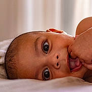 Aaron participe au concours pour gagner de l'argent avec cette photo : baby, close_up, face, hand, fingers, curious, lying_down, skin, eyes, infant, portrait, soft_light, expression, child, mouth, tongue, indoors, natural_light, young, cute