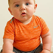 Teddy joined the competition — help win amazing prizes! baby, child, infant, orange_shirt, sitting, floor, curious, cute, portrait, skin, hands, feet, indoor, young, human, person, face, eyes, expression, casual_clothing