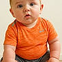 baby, child, infant, orange_shirt, sitting, floor, curious, cute, portrait, skin, hands, feet, indoor, young, human, person, face, eyes, expression, casual_clothing