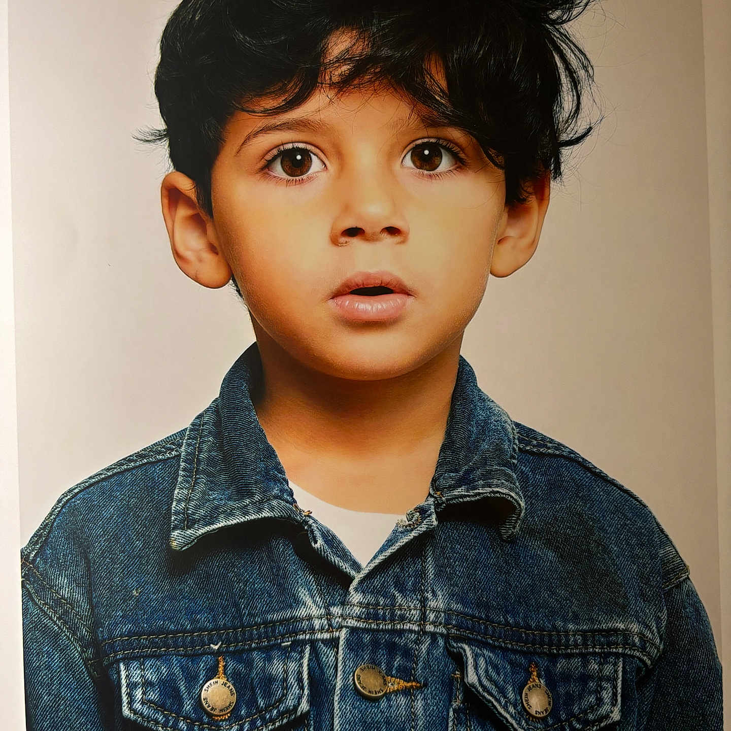 Anes Emir participe au concours pour gagner de l'argent avec cette photo : child, boy, denim_jacket, portrait, face, brown_eyes, hair, casual_clothing, curious_expression, studio_lighting, young, fashion, innocence, closeup, person, front_view, real_photo, indoor, neutral_background, head_and_shoulders