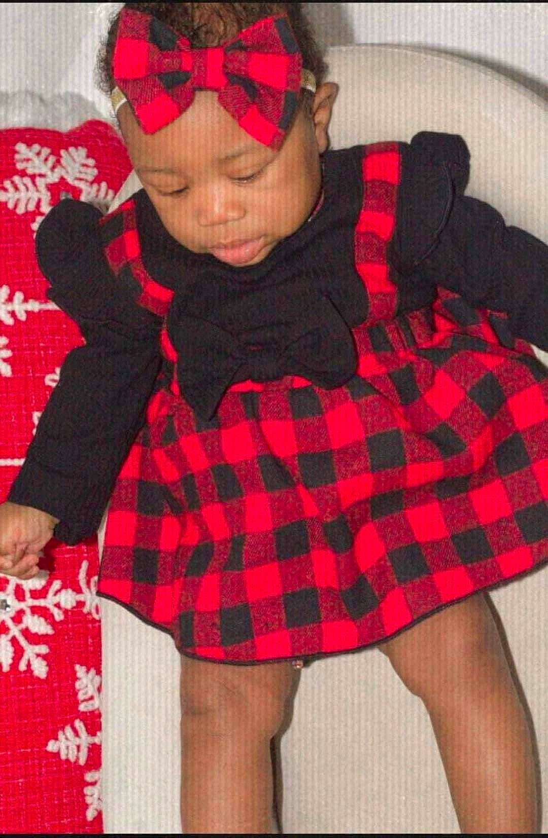 Elia is registered to the contest to win money with this photo: baby_toddler_clothing, black, child, face, goggles, head, headwear, human_leg, knee, leg, outerwear, pattern, person, pink, plaid, red, sleeve, sock, tartan, textile