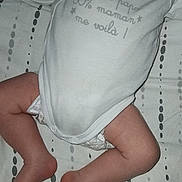 Ilyan a rejoint le concours — aidez-le/la à gagner de superbes lots ! arm, baby, bed, child, clothing, diaper, foot, hand, indoor, infant, leg, lying_down, onesie, pattern, person, sheet, skin, sleeping, soft_lighting, text_on_clothing