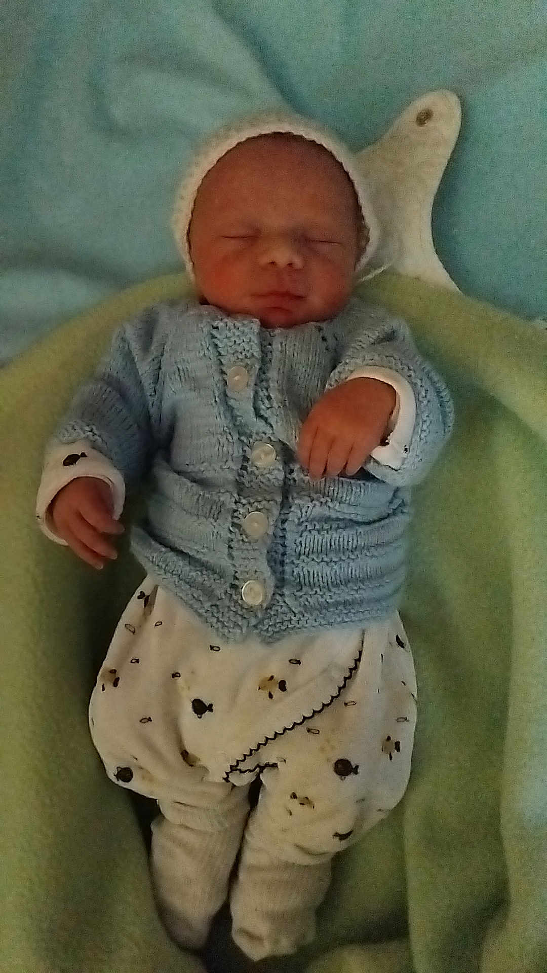 Ilyan a rejoint le concours — aidez-le/la à gagner de superbes lots ! newborn, baby, sleeping, knitted_clothing, blue_sweater, white_pants, patterned_pants, blanket, soft, cozy, infant, cute, resting, child, small_hands, headwear, warm, indoors, portrait, peaceful