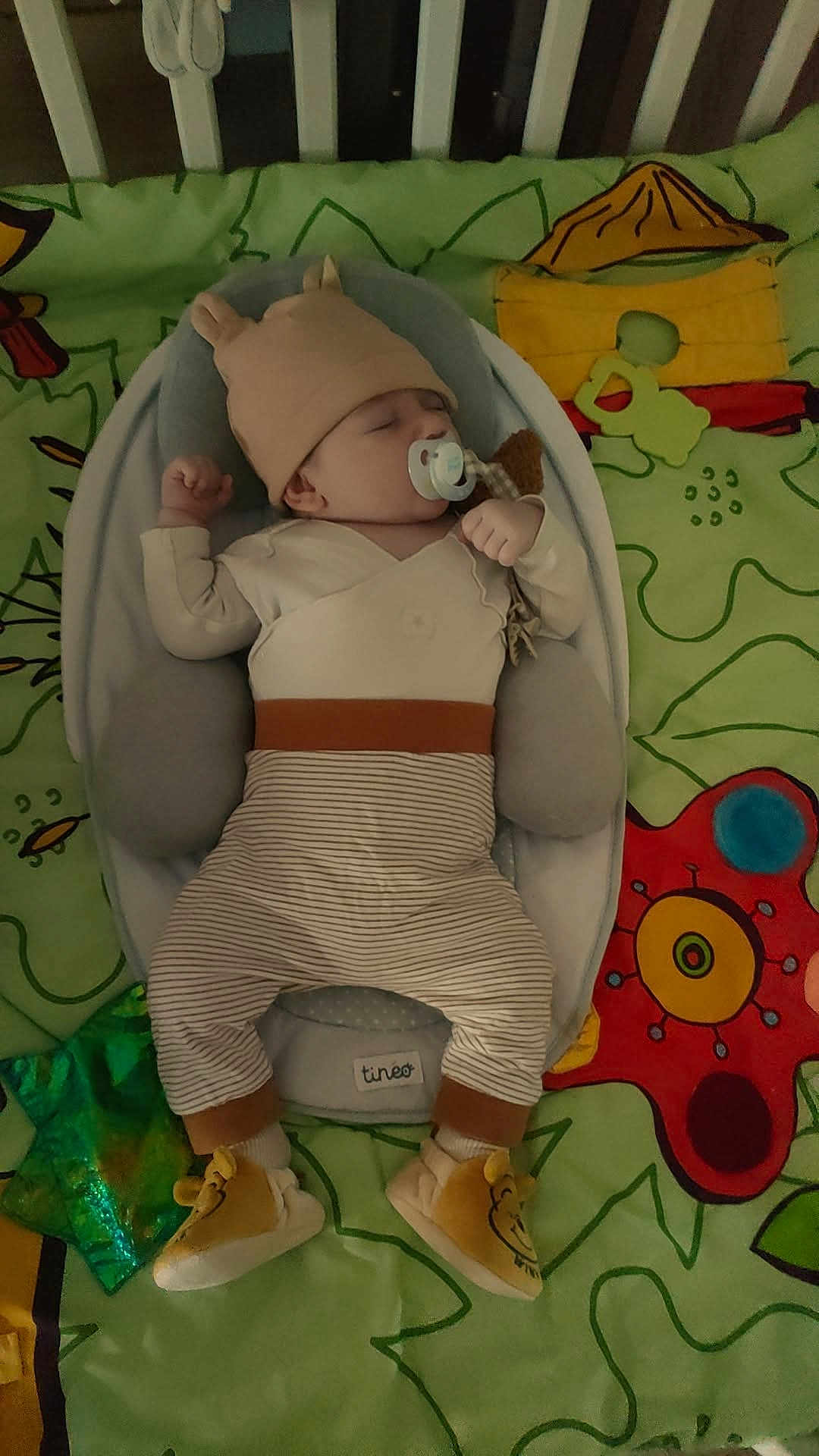 Simon participe au concours pour gagner de l'argent avec cette photo : baby, sleeping, hat, pacifier, baby_lounger, striped_pants, yellow_booties, play_mat, colorful_toys, crib, infant, cozy, cute, child, indoors, resting, toddler, soft_toys, comfort, peaceful