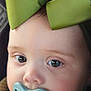 Athena is registered to the contest to win money with this photo: baby, child, pacifier, green_bow, car_seat, close_up, face, headwear, infant, cute, soft_lighting, expression, young_child, indoors, seatbelt, clothing, portrait, skin, eyes, nose