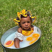 Analeia is registered to the contest to win money with this photo: baby, child, tub, metal, milk_bath, citrus, orange_slices, grapefruit, yellow_bow, hat, outdoor, grass, summer, sunlight, cute, portrait, water, skin, infant, playful