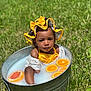 baby, child, tub, metal, milk_bath, citrus, orange_slices, grapefruit, yellow_bow, hat, outdoor, grass, summer, sunlight, cute, portrait, water, skin, infant, playful