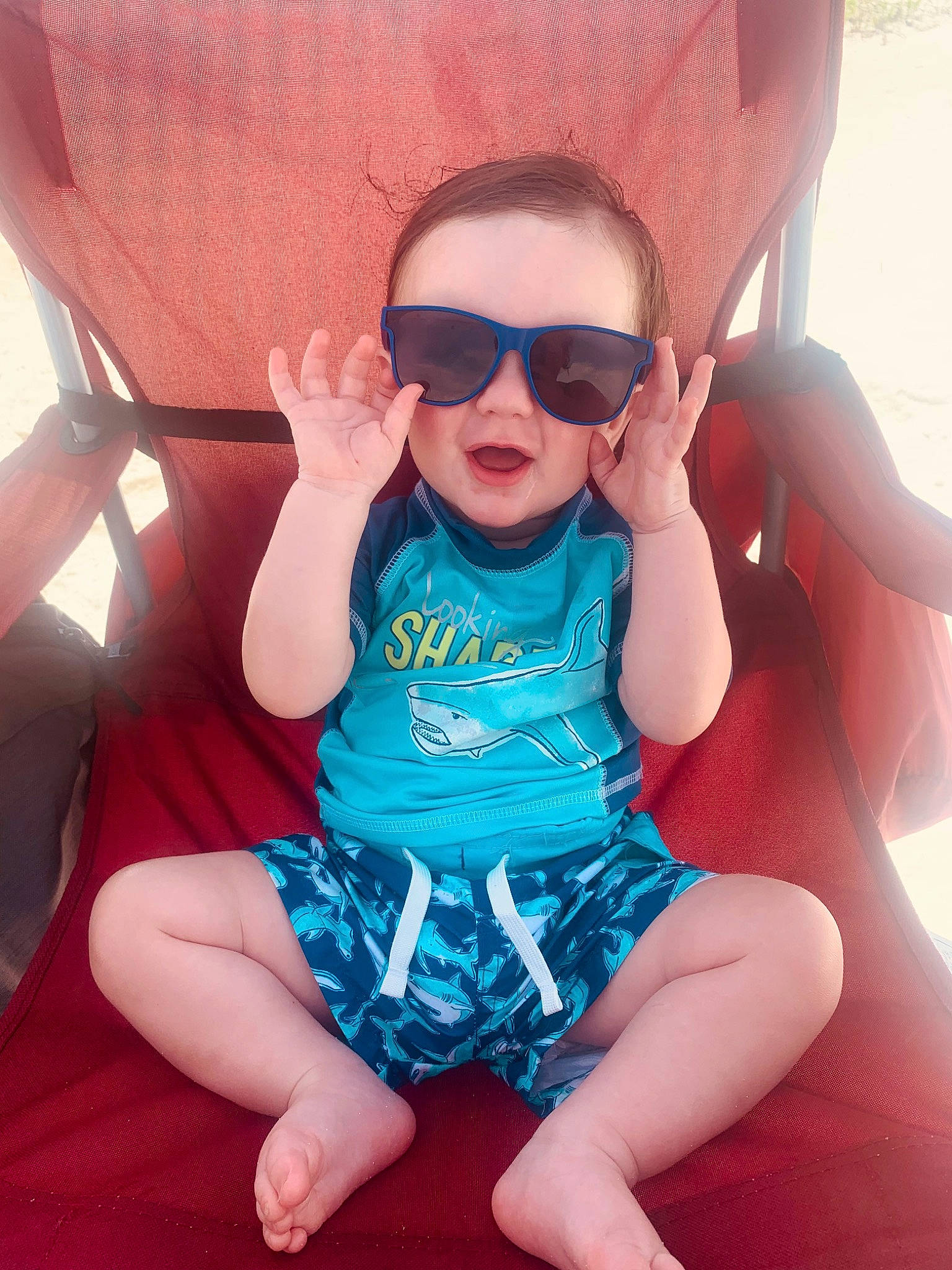 Kolton is registered to the contest to win money with this photo: arm, baby_toddler_clothing, cool, eyewear, finger, glasses, goggles, hand, happy, leg, lip, mouth, person, pink, product, red, skin, sleeve, sunglasses, thigh