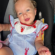 Charlotte is registered to the contest to win money with this photo: toddler, child, curly_hair, blue_eyes, smiling, car_seat, clothing, striped, lobster_pattern, happy, face, person, infant, cute, baby, apparel, seat, indoor, portrait, young_child