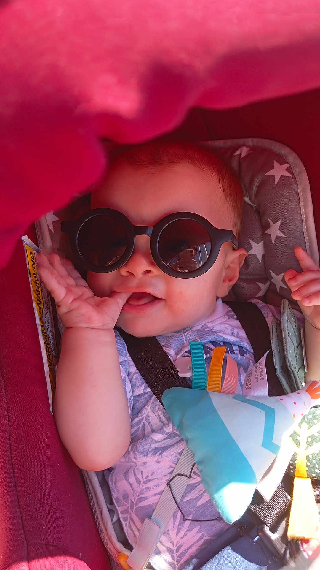 Emillyo participe au concours pour gagner de l'argent avec cette photo : baby, sunglasses, car_seat, toy, infant, child, thumb_sucking, playful, colorful, sunlight, fabric, seatbelt, cute, smiling, indoor, closeup, accessory, fun, relaxed, person