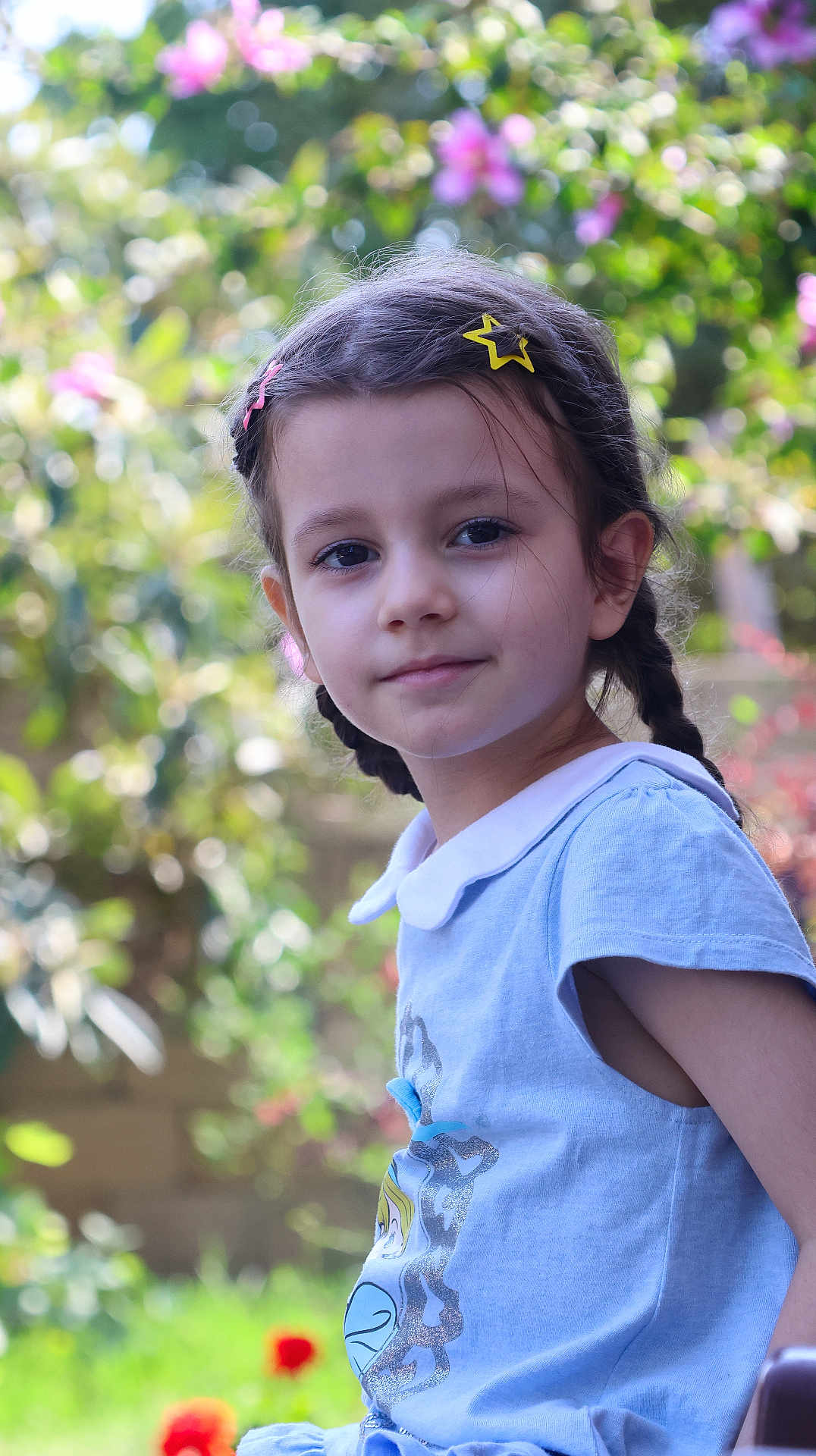 Aylin joined the competition — help win amazing prizes! child, girl, braids, hair_clips, outdoor, garden, flowers, greenery, portrait, smile, blue_dress, collar, sunlight, nature, young, cute, happy, face, childhood, peaceful