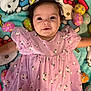 baby, child, pink_dress, floral_pattern, hello_kitty, blanket, easter_eggs, colorful, cute, smiling, portrait, indoors, young_child, soft_lighting, happy, infant, person, lying_down, decorative, playful