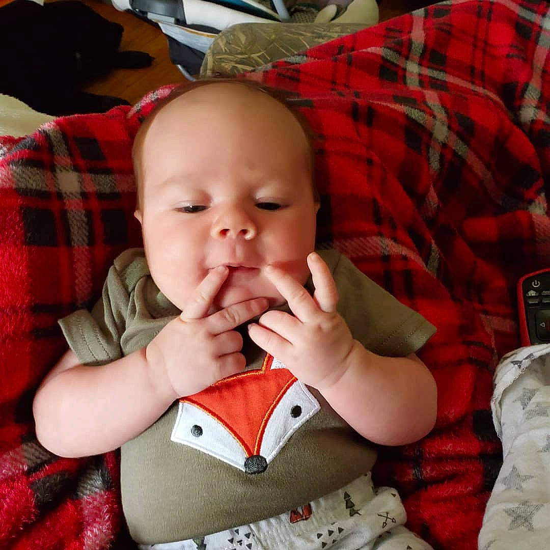 Hayden is registered to the contest to win money with this photo: baby, carmine, cheek, child, design, facial_expression, finger, lip, mouth, nose, pattern, person, plaid, smile, thumb, toddler, yawn