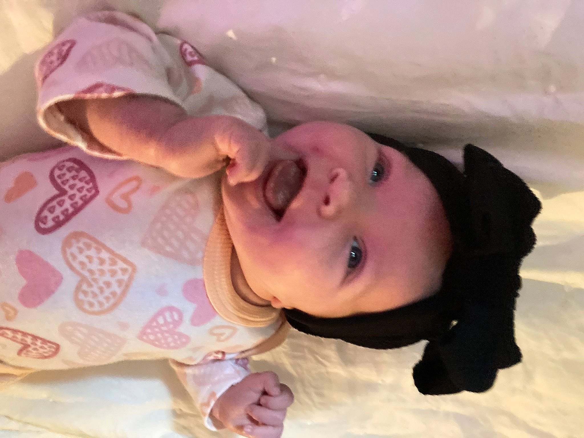 Amira is registered to the contest to win money with this photo: baby, cheek, child, comfort, ear, eyebrow, eyelash, finger, happy, headgear, headwear, human_body, lip, mouth, nose, person, pink, skin, sleeve, smile