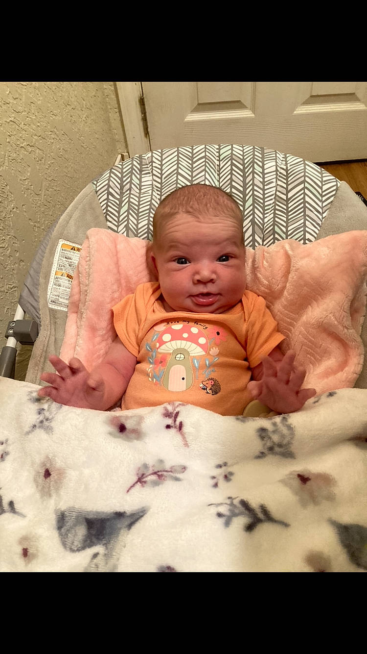 Amira is registered to the contest to win money with this photo: abdomen, baby, baby_toddler_clothing, bedding, bedtime, cheek, child, comfort, event, eye, face, finger, head, linens, mammal, mouth, person, room, skin, sleeve