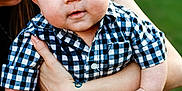 Jace is registered to the contest to win money with this photo: baby, child, blue_eyes, checkered_shirt, holding, adult, smile, outdoor, green_background, person, closeup, portrait, skin, hands, face, cute, infant, casual_clothing, summer, happy