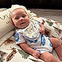 Jace is registered to the contest to win money with this photo: baby, smiling, infant, bib, pillow, woodland_print, reclining, indoor, cozy, clothing, nike, happy, child, face, person, cute, comfort, pattern, young, relaxing
