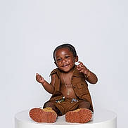 Maison joined the competition — help win amazing prizes! child, toddler, portrait, smiling, sitting, fashion, outfit, brown_clothing, braids, necklace, bracelet, shoes, sneakers, studio, white_background, pedestal, posing, happy, fashion_photography, full_body