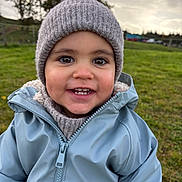 Marius a rejoint le concours — aidez-le/la à gagner de superbes lots ! toddler, child, smiling, hat, jacket, outdoor, grass, field, cloudy_sky, happy, face, portrait, winter_clothing, cute, young_child, nature, person, warm_clothing, headwear, daylight