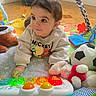 baby, child, toy, plush_toy, colorful, play_mat, floor, sweatshirt, mickey_mouse, indoor, cute, infant, piano_toy, bright_colors, expression, person, young, crawling, wooden_floor, soft_toys