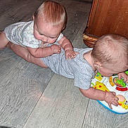 Tessa is registered to the contest to win money with this photo: baby, infant, floor, toy, playtime, wooden_floor, child, cute, indoor, clothing, hand, footwear, socks, furniture, crawling, interaction, person, toddler, curious, holding