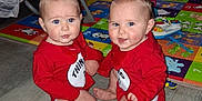 Tessa is registered to the contest to win money with this photo: baby, infant, child, toddler, red_clothing, matching_outfits, floor, play_mat, toy, indoor, person, cute, blue_eyes, sitting, expression, furniture, baby_gear, play, home, smile