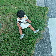 Bhargav Ram joined the competition — help win amazing prizes! casual_clothing, child, curious, curly_hair, daylight, footwear, grass, greenery, mickey_mouse, nature, outdoor, pavement, person, playful, shirt, sidewalk, sitting, toddler, white_shoes, young_child