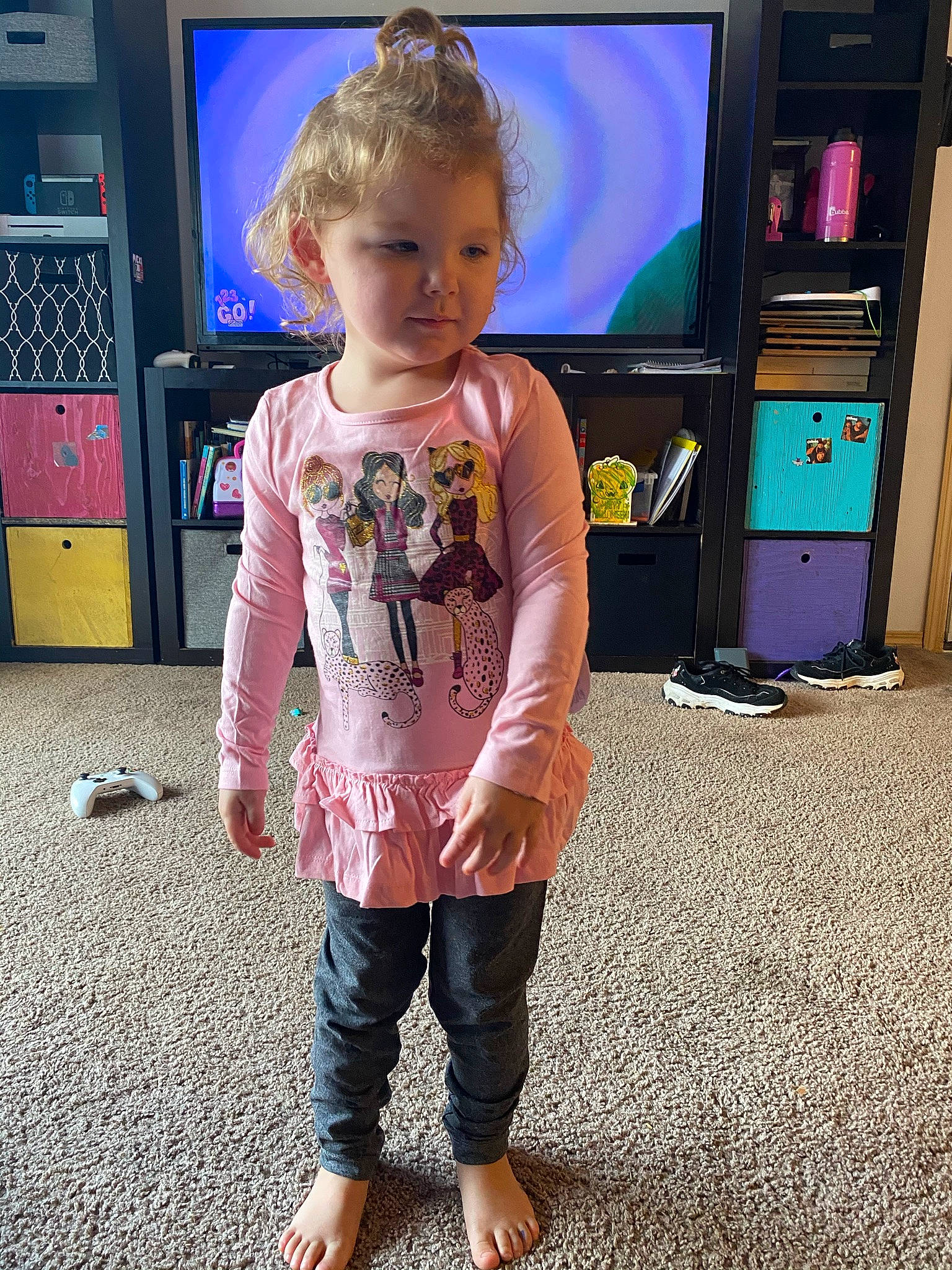 Haylie is registered to the contest to win money with this photo: child, face, floor, flooring, fun, hair, hand, happy, head, home_appliance, joint, leg, person, shoulder, sleeve, standing, t_shirt, television, television_set, toddler