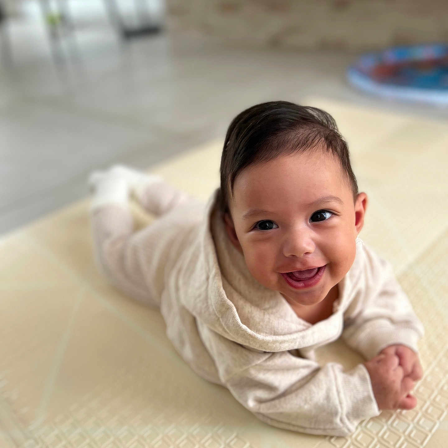 Eden a rejoint le concours — aidez-le/la à gagner de superbes lots ! baby, beige_outfit, blurred_background, child, cozy, cute, eyes, face, floor, hair, hands, happy, indoors, infant, mat, portrait, skin, smiling, tummy, young_child