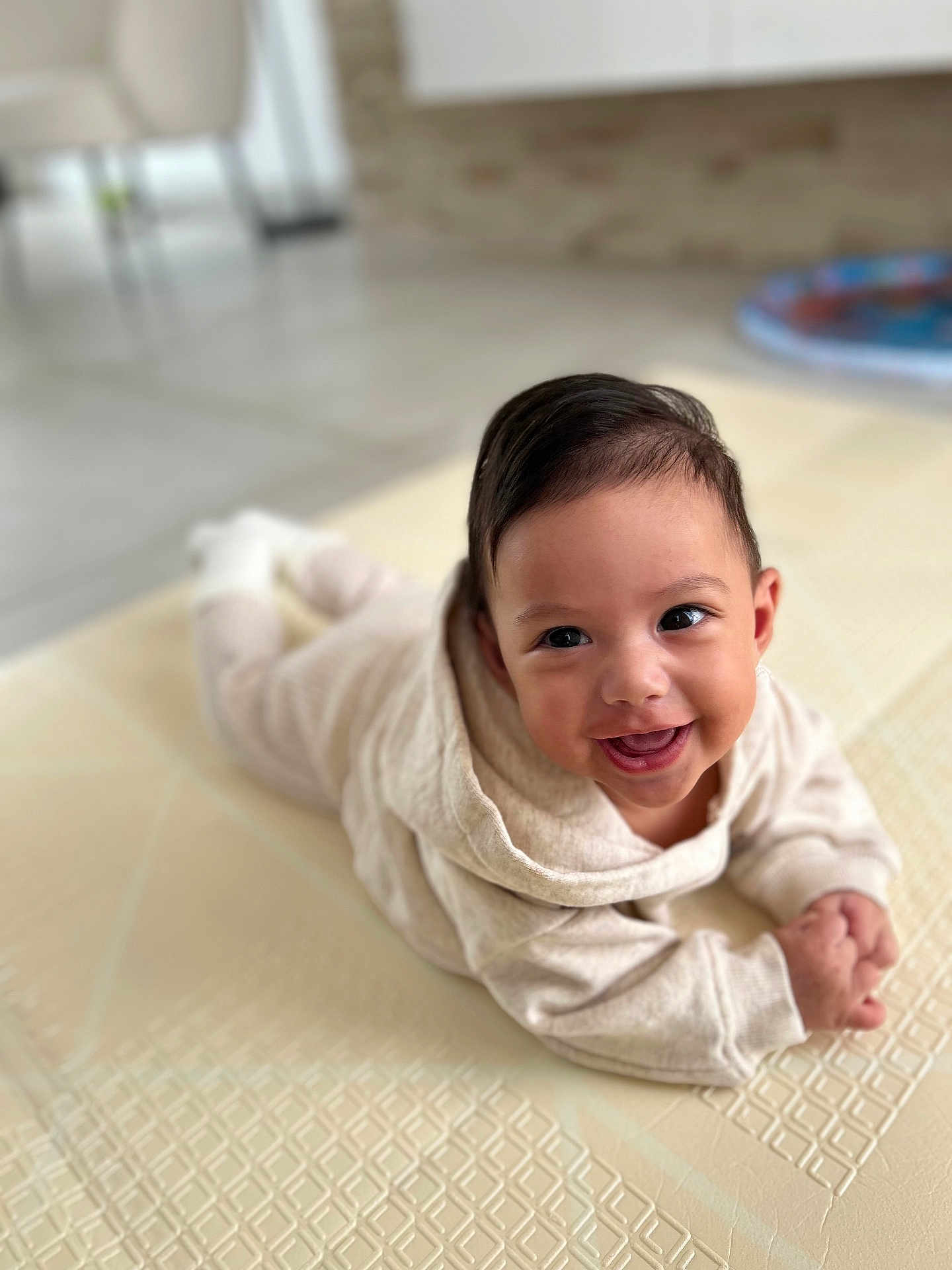 Eden a rejoint le concours — aidez-le/la à gagner de superbes lots ! baby, smiling, tummy, mat, beige_outfit, indoors, child, cute, happy, face, infant, portrait, cozy, young_child, skin, hair, hands, floor, blurred_background, eyes
