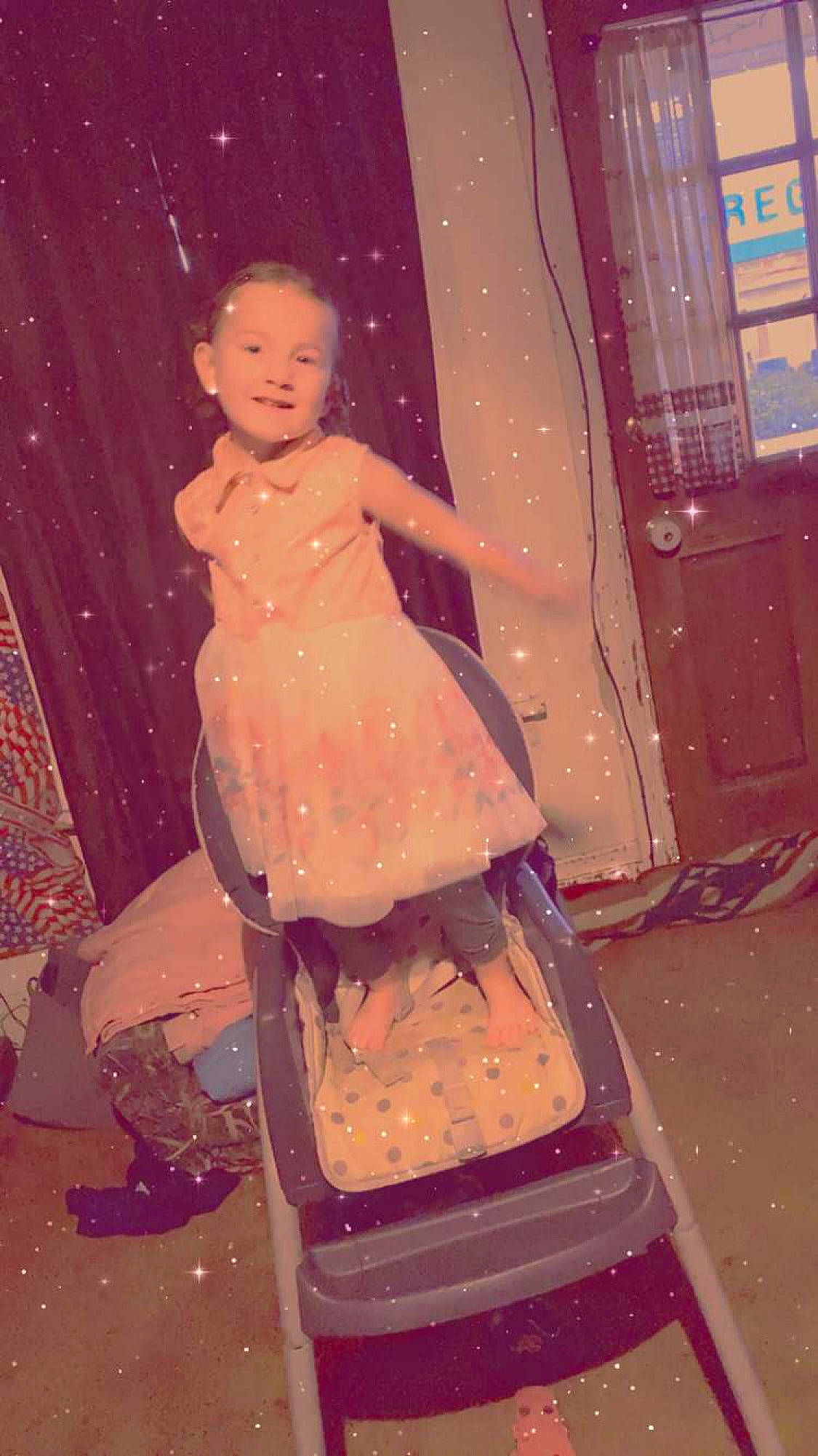 Stella is registered to the contest to win money with this photo: child, curtain, entertainment, event, fashion, fashion_design, fun, human, human_body, human_leg, magenta, pattern, peach, person, pink, purple, recreation, room, sandal, sitting