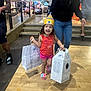 Janay is registered to the contest to win money with this photo: casual_wear, celebration, child, colorful_clothing, curly_hair, family, footwear, girl, happy, indoor, joyful, mall, party_hat, people, playful, retail, shopping, shopping_bags, smiling, stairs